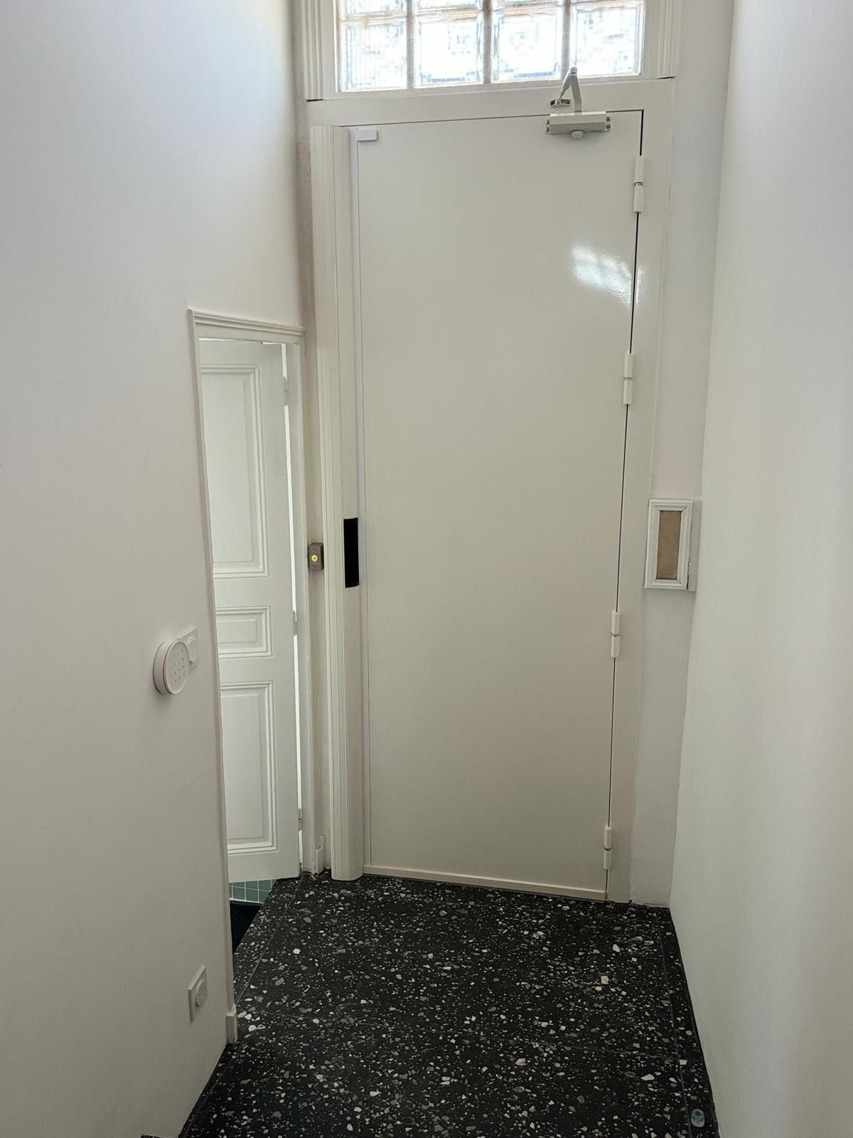 Porte blindée blanche avec ferme-porte en immeuble